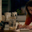 Frame grab from Earthquake Note of Kat Foster in a medium shot writing on a notepad