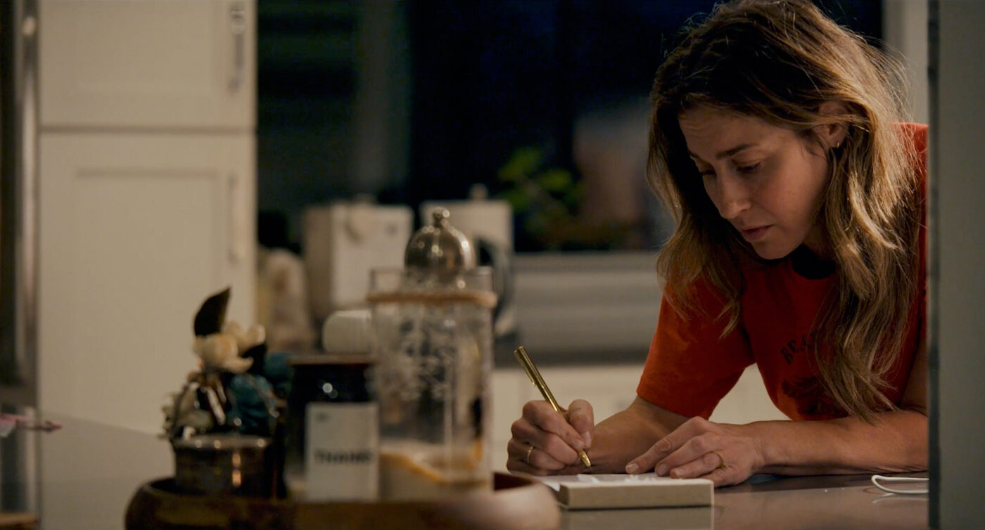 Frame grab from Earthquake Note of Kat Foster in a medium shot writing on a notepad