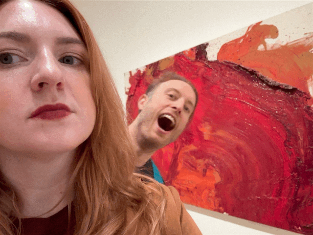 Dustin and Aubrey posing playfully in front of a painting at MoMA