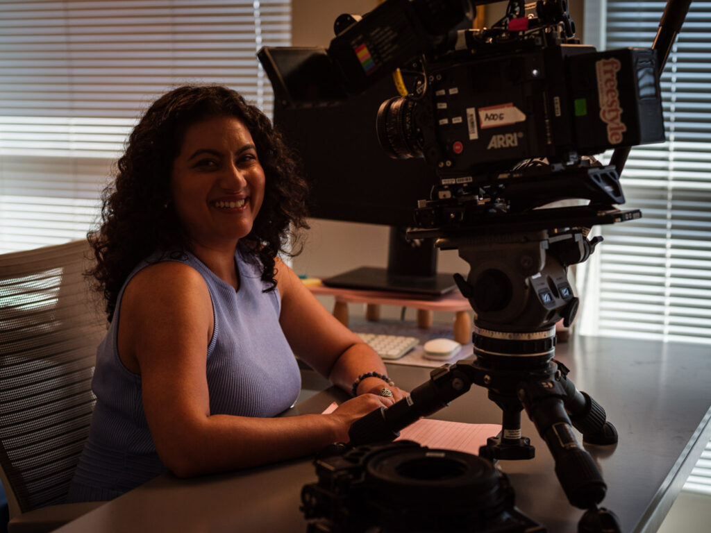 a large camera sits on a desk very close to Ashna Sharan