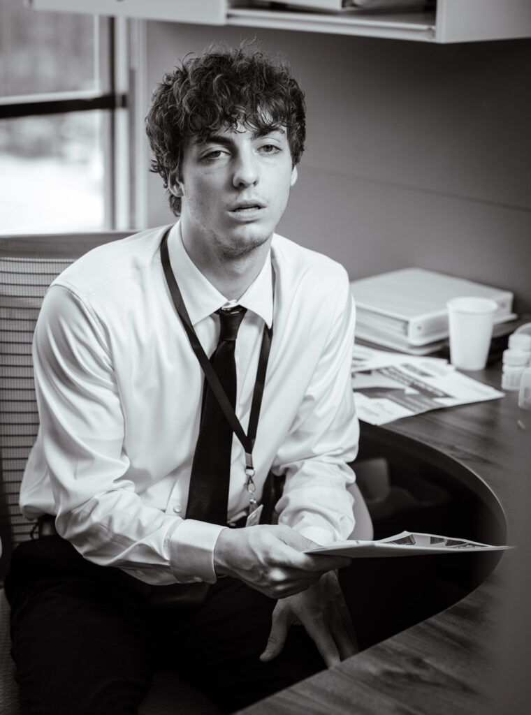 A man holds a piece of paper in an office and looks ill