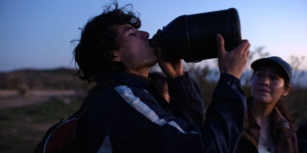 Frame grab from Illegal Aliens of a migrant drinking from a water jug at sunset