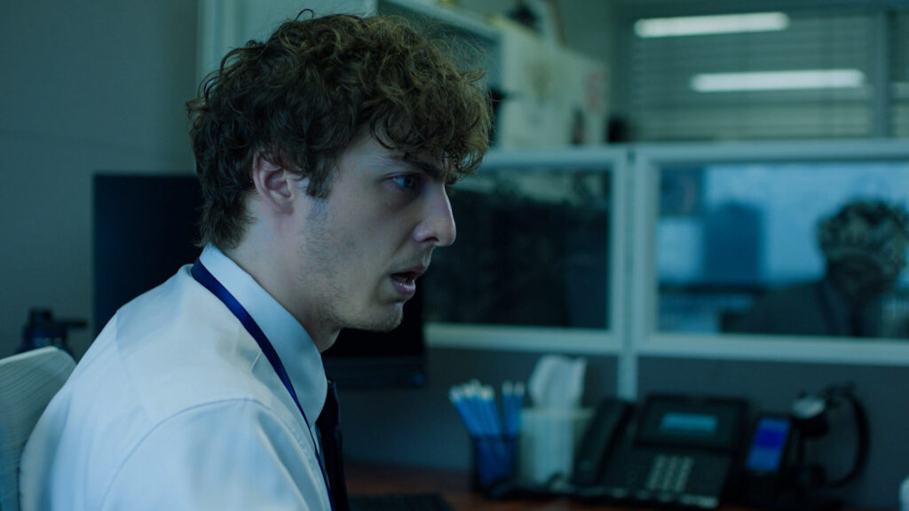 From Sick Days, a man in profile sitting in a cubicle